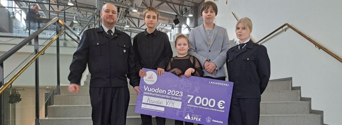 Kouvolan VPK:laisia poseeraa lahjashekin kanssa.